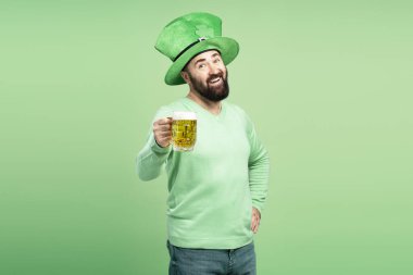 Happy man wearing green leprechaun hat offering pint of beer celebrating St. Patrick's Day clipart