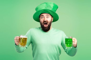 Yeşil cüce şapkalı sakallı adam, kazak, iki kupa tutuyor, biri yeşil, biri sarı biralı, Aziz Patrick Günü 'nü kutluyor.