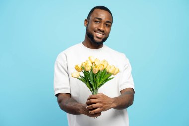 Romantik bir adam hediye olarak sarı lale buketi tutuyor, yıldönümünü ya da Sevgililer Günü 'nü kutluyor.