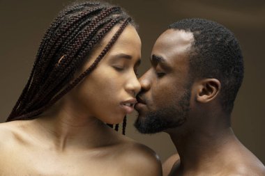 Romantik çift, tutkulu bir öpücüğü kapalı gözlerle paylaşıyor. Huzurlu bir yakınlık anında sevgi ve şefkat yayıyorlar.