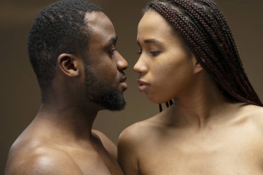 Üstsüz Afro-Amerikan modeller birbirlerine sevgi ve tutkuyla bakıyor, bir anlık yakınlık paylaşıyorlar.