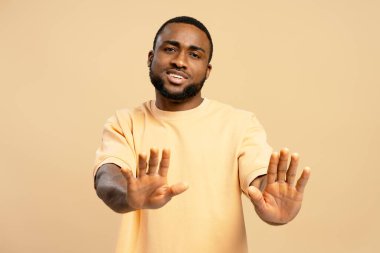 Genç Afrikalı Amerikalı adam iki eliyle dur işareti yapıyor. İnkar, ret, uyarı veya reddetme.