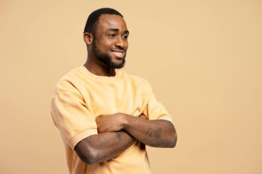 Genç bir Afrikalı Amerikalının stüdyo portresi gülümseyen ve kollarını kavuşturan, kendine güvenini ve pozitifliğini ifade eden