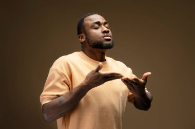 Umut dolu Afrikalı Amerikalı adam, gözleri kapalı ve elleri açık, Tanrı 'ya içtenlikle dua ediyor, dingin bir anda inanç ve bağlılığı somutlaştırıyor.