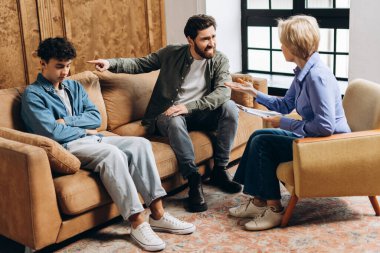Öfkeli bir babanın portresi genç oğluyla ruh sağlığı uzmanı ile görüşürken. Aile sorunları, gençlik sorunları, terapist, tavsiye, yardım kavramı