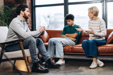 Erkek psikoloğa genç oğluyla ilgili sorunu açıklayan üzgün kadının portresi. Danışmanlık terapisi. Psikoloji tedavisi