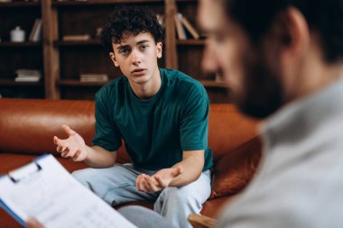 Stresli genç çocuk terapi seansı sırasında erkek psikanalistle olan sorunundan bahsediyor. Danışmanlık terapisi. Psikoloji tedavisi