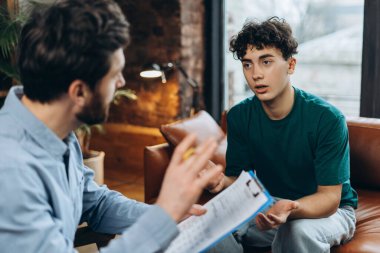 Erkek psikiyatristle psikoterapi seansında genç bir çocuğun portresi. Psikoterapi hizmetleri, ruhsal sağlık profesyonel konsepti