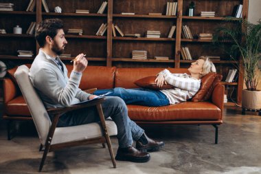 Terapi seansında kadın hastasına not alan erkek terapistin portresi. Psikolojik destek kavramı