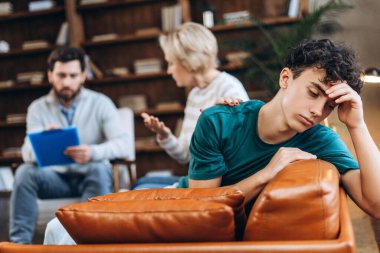 Annesi ve psikoloğu seansta konuşurken üzgün genç çocuğun portresi. Danışmanlık terapisi. Psikoloji tedavisi