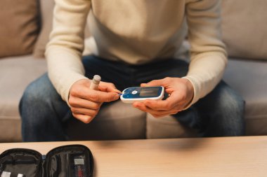 Adam glukometreyle glikoz seviyesini test ediyor. Evde ellere odaklanıyor. Sağlık hizmeti kavramı