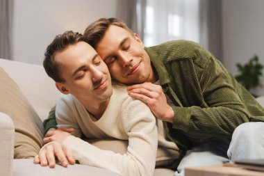 İki erkek, romantik eşcinsel çift, kanepede kapalı gözlerle sarılıyorlar, samimiyet ve şefkatin tadını çıkarıyorlar. Aşk, ilişki kavramı