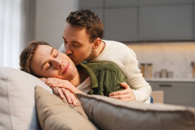 Romantik eşcinsel çift oturma odasında kanepede öpüşerek hassas bir anı paylaşıyor. Aşk, ilişki kavramı