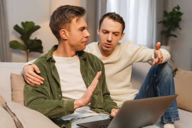 İki erkek meslektaşı evde dizüstü bilgisayarla çalışırken anlaşmazlık yaşıyorlar. Çevrimiçi teknoloji kavramı
