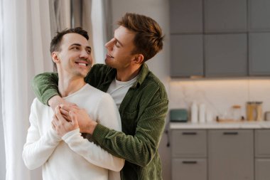 Romantik eşcinsel çift, modern mutfaklarında birbirlerine sarılıp el ele tutuşuyorlar. Lgbt, aşk, ilişki kavramı