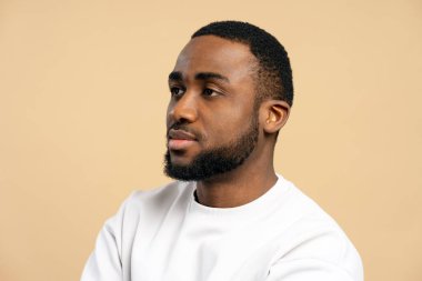 Beyaz kazak giyen düşünceli bir Afrikalı Amerikalı 'nın, bej bir arka planda kameradan uzağa bakan düşünceli, genç bir adamın portresi, tefekkür ya da içgözlem duygusu aktarıyor.