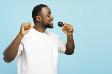 Beyaz bir tişört giyen, mikrofon tutan, mavi arka planda şarkı söyleyen, müzikten hoşlanan ve pozitif duygular ifade eden Afro-Amerikalı bir adam. Reklam kavramı