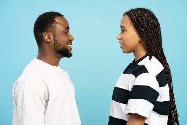 Genç adam ve kadın yüz yüze, gülümseyen ve konuşan, mavi bir arka planda, iletişimi, dostluğu ve olumlu duyguları temsil eden. Aşk, reklam konsepti