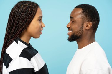 Mavi bir arka planda birbirlerine bakıp gülümseyen, aşkı, suç ortaklığını ve mutluluğu tasvir eden genç bir Afrikalı Amerikalı çiftin profili. Aşk konsepti