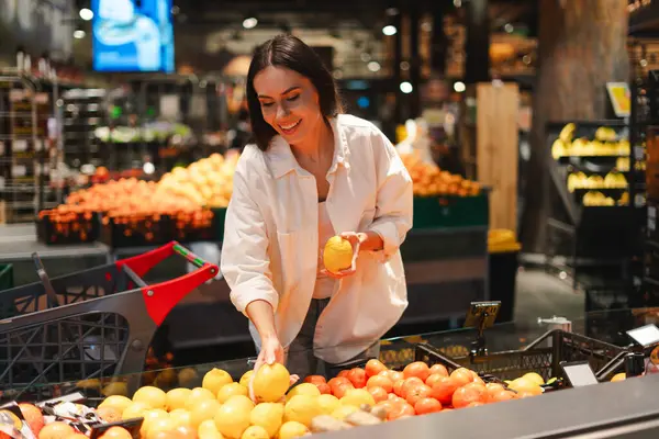 Mutlu müşteri marketten taze limon ve mandalina seçiyor, sağlıklı bir diyet için besleyici malzemeler seçerken alışveriş deneyiminin tadını çıkarıyor. Yiyecek konsepti