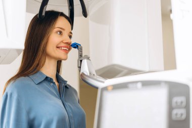 Kadın hastanın portresi klinikteki röntgende dişlerin panoramik röntgenini çekiyor. Diş tedavisi, radyoloji, panoramik tarayıcı