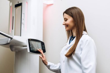 Kadın dişçinin portresi sağlık merkezinde röntgen mi çekilecek? Dokunmatik ekrandaki bir düğmeye bas. Bilgisayar diş tanıları