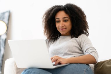 İnternette çalışan, dizüstü bilgisayarı kullanan, klavyeye yazı yazan, internete takılan, evdeki kanepede oturmaktan keyif alan kadın serbest çalışan.