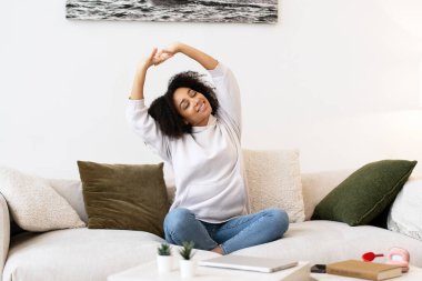 Parlak oturma odasındaki rahat kanepeye uzanan, dizüstü bilgisayardaki işini bitirdikten sonra evde tatilin tadını çıkaran mutlu serbest yazar.