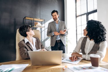 İş adamları birlikte çalışıp finansal tablet ve dizüstü bilgisayar kullanıyorlar.