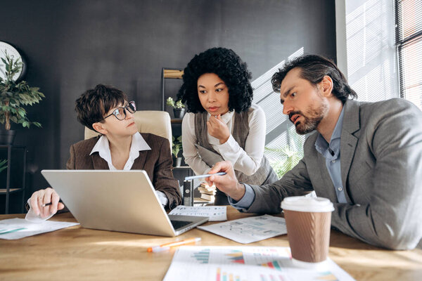 Коллеги по бизнесу участвуют в дискуссии о стратегии проекта во время встречи в современном офисе, окруженном технологиями и командной работой