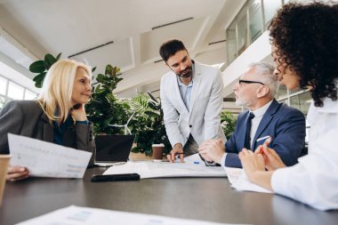 Sürdürülebilir bir projenin planlarını analiz eden çok ırklı iş adamları, modern ofis ortamında fabrikalar ve minyatür rüzgar türbinleriyle ortak bir tartışmaya giriştiler. Başlangıç konsepti