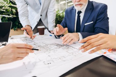 Mimarlar ve mühendisler bir plan üzerinde işbirliği yaparak, inşaat planı için başarılı bir uygulama ve yenilikçi çözümler sağlamak için tasarım stratejileri ve proje ayrıntılarını tartıştılar.