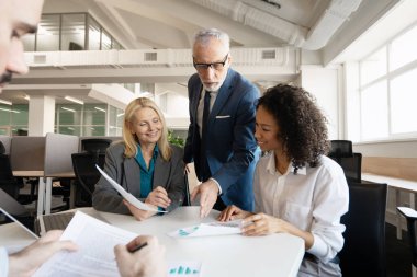 Gülümseyen, kendinden emin, çok uluslu bir grup modern ofisteki mali raporları analiz ediyor. Beyin fırtınası konsepti