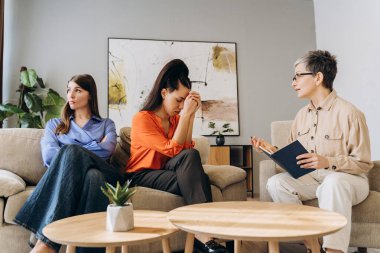 Psikolog, üzgün hastaları dikkatle dinlerken kanepedeki terapi seanslarında mücadelelerini paylaşırken destek ve anlayış ortamı yaratıyor.