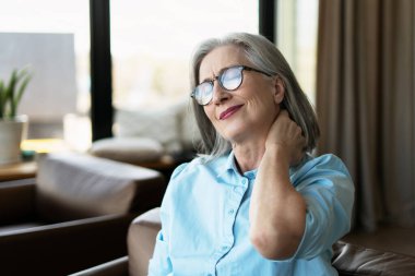 Üst düzey iş kadını boynuna masaj yapıyor, bilgisayardaki uzun çalışmalardan sonra kasları kasılmış.
