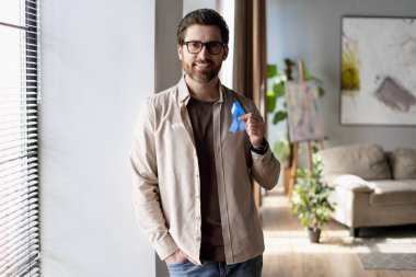 Kolon kanserini, prostat kanserini ve Alzheimer hastalığını destekleyen mavi kurdele gösteren gülümseyen adam