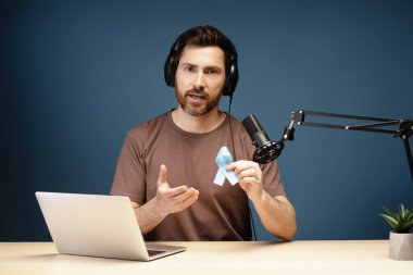 Radyo sunucusu, prostat kanseri farkındalığını sembolize ederken aynı zamanda mikrofon ve kulaklıkla podcast kaydı yapıyor.