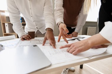 Mimarlar inşaat planlarını incelerken işbirlikçi bir tartışmaya giriştiler, verimli bir toplantı sırasında proje ayrıntıları üzerinde strateji oluşturdular