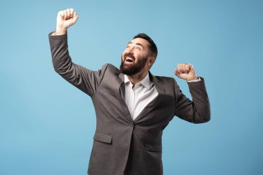 Zaferi kutlayan coşkulu işadamı, kollarını kaldırmış ve yumruklarını sıkarak sevinç ve başarısını dile getiriyor.