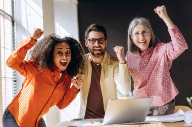 Mimarlar başarılı bir projeyi bir dizüstü bilgisayarla kutlarken, takım çalışmasını ve başarıyı canlı bir ofis ortamında somutlaştırırken kutluyorlar