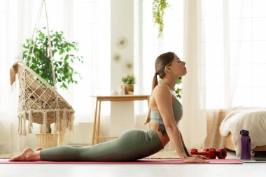 Parlak ve havadar yatak odasında sabah yogası sırasında Asana 'ya bakan bir kadın.