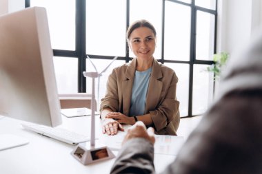 İş kadını, masanda minyatür rüzgar türbini modeliyle yenilenebilir enerji projesini tartışıyor