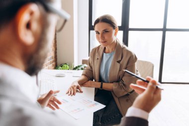 İş arkadaşları bir ofis toplantısı sırasında pazarlama stratejisi, işbirliği ve takım çalışmasının teşvik edilmesi hakkında canlı bir tartışmaya giriştiler