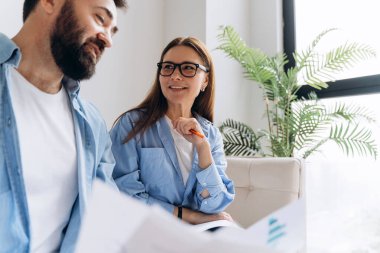 Modern ofiste resmi olmayan toplantılarda belgeleri analiz eden ve projeyi tartışan iş ortakları