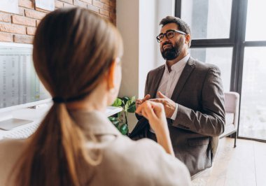 İş adamı, modern ofis ortamında iş arkadaşıyla stratejiyi tartışıyor, geniş bir pencerenin yanında görüşleri ve fikirleri paylaşıyor.