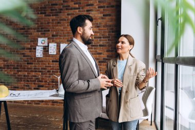Modern ofiste proje detaylarını planlar ve rüzgar türbini modelleriyle tartışan iki mimar
