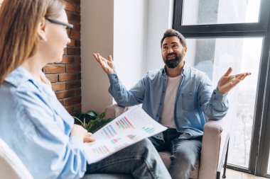İş adamı, ofisteki bir toplantıda kadın meslektaşına çizelgeleri gösteren pazarlama stratejisini anlatıyor.
