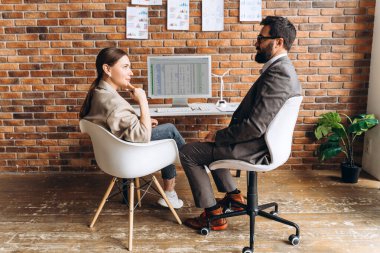 İki iş ortağı bir bilgisayarın önünde oturmuş yenilenebilir enerji yatırım verilerini görselleştiriyor ve stratejilerini tartışıyorlar.