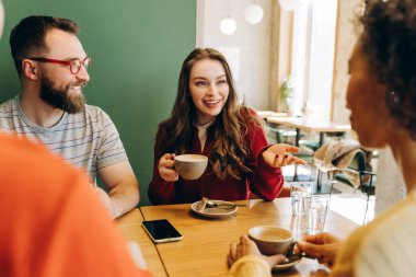 Modern bir kafede kahve içerken sohbet eden, hikayelerini paylaşan ve gelişigüzel ilişkiler kuran bir grup yetişkin. İletişim konsepti