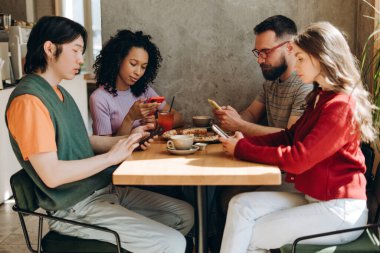 Dört arkadaş bir kafede bir masada oturmuş, pizza ve içkinin tadını çıkarıyorlar, ama hepsi akıllı telefonlarına dalmış, birbirlerini görmezden geliyorlar. Çevrimiçi teknoloji kavramı